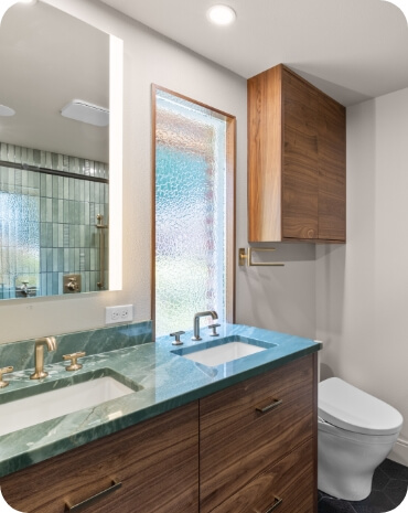 Close-up of a green marble bathroom counter with gold faucets and a modern aesthetic.