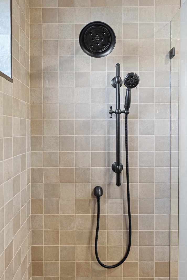  A sleek modern black shower head against a tiled wall.